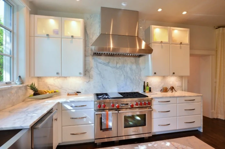 Modern white kitchen with marble countertops and a professional stainless steel range